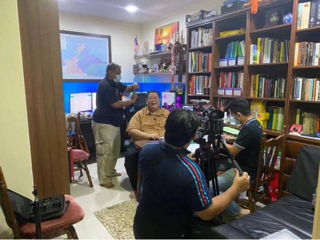 Documentary crew recording an interview among the bookshelves
