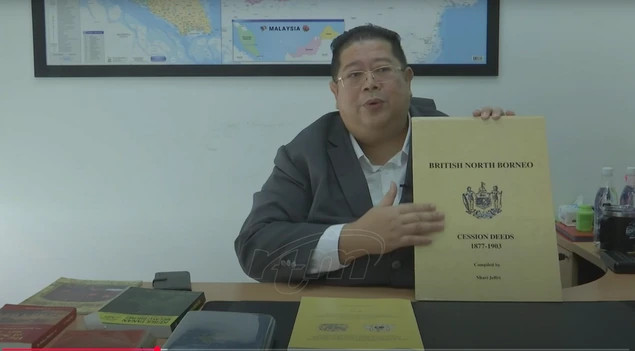 Shari Jeffri showing a historical publication in the RTM documentary