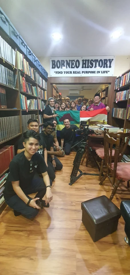 Participants beside the flag and bookshelves