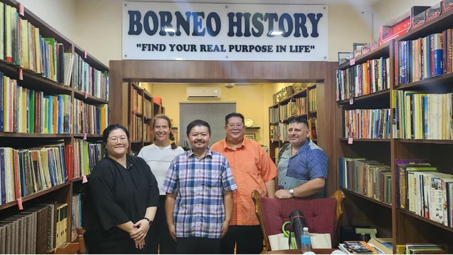 Visitors and Shari Jeffri beside the gallery bookshelves