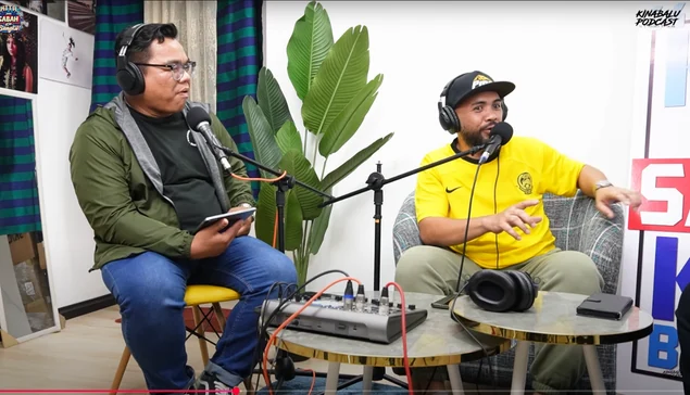 The podcast hosts seated at their microphones
